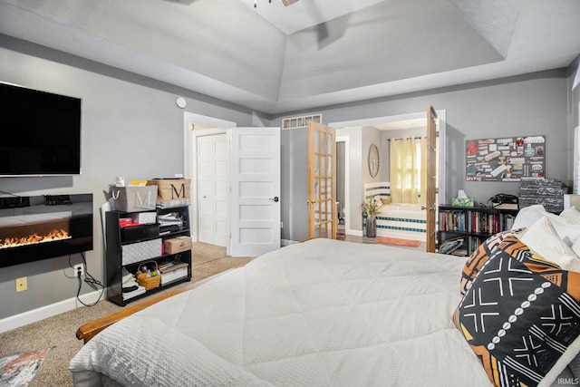 55705 Sichuan Dr, Osceola, IN 46561 - bedroom featuring a raised ceiling, carpet floors, baseboards, ensuite bathroom, and a glass covered fireplace