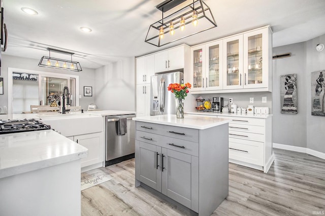 55705 Sichuan Dr, Osceola, IN 46561 - kitchen with stainless steel appliances, light wood finished floors, pendant lighting, glass insert cabinets, and white cabinetry