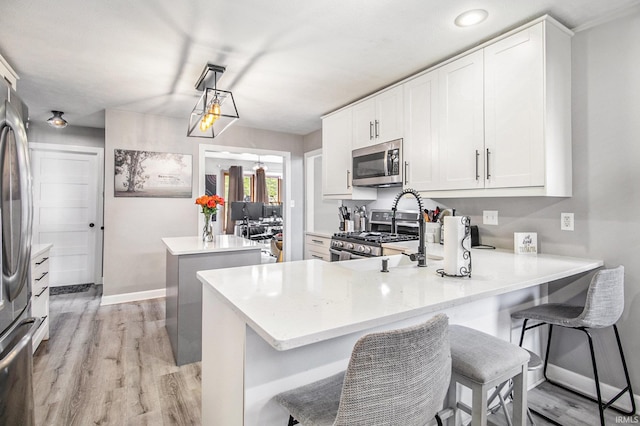 55705 Sichuan Dr, Osceola, IN 46561 - kitchen featuring stainless steel appliances, a kitchen island, baseboards, light wood finished floors, and a peninsula