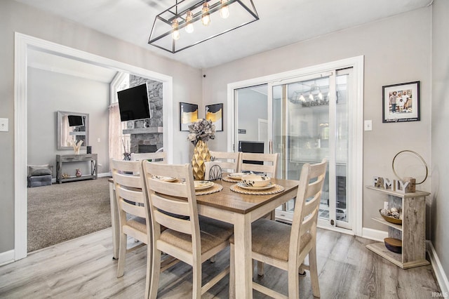 55705 Sichuan Dr, Osceola, IN 46561 - dining room with a chandelier, light wood finished floors, a fireplace, and baseboards