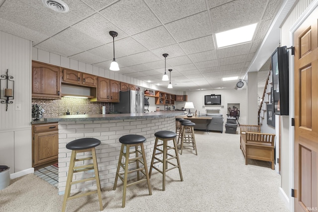 1365 W 15th St, Jasper, IN 47546 - kitchen featuring freestanding refrigerator, dark countertops, open floor plan, light carpet, and a kitchen bar