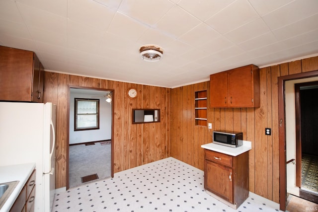 2331 N 24th St, Lafayette, IN 47904 - kitchen featuring brown cabinets, freestanding refrigerator, wood walls, and light countertops