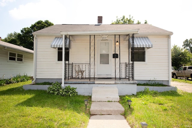 2331 N 24th St, Lafayette, IN 47904 - bungalow-style house with covered porch, a chimney, a front lawn, and a shingled roof