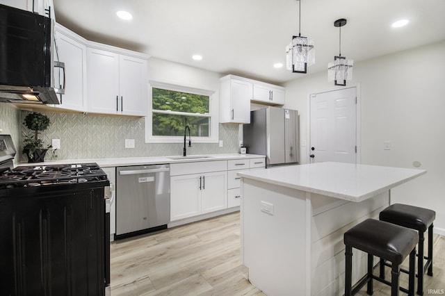 61156 Old Spanish Trl, South Bend, IN 46614 - kitchen featuring appliances with stainless steel finishes, a sink, light wood-type flooring, backsplash, and a kitchen bar