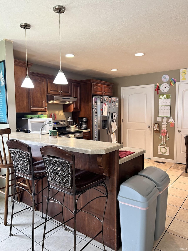1406 Hillcrest Rd, Bedford, IN 47421 - kitchen with appliances with stainless steel finishes, light countertops, a peninsula, under cabinet range hood, and a kitchen bar