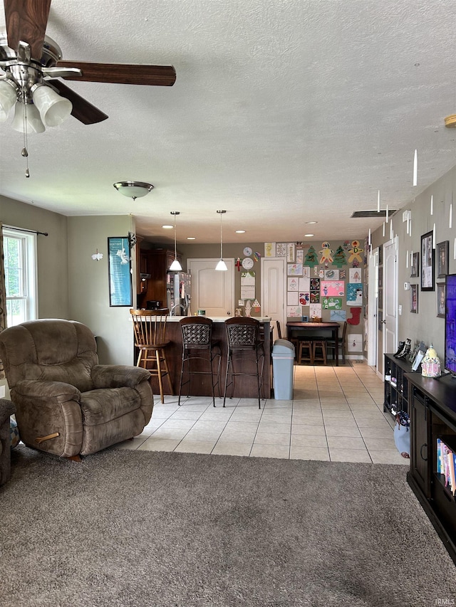 1406 Hillcrest Rd, Bedford, IN 47421 - living area featuring a textured ceiling, a ceiling fan, light tile patterned floors, and light colored carpet