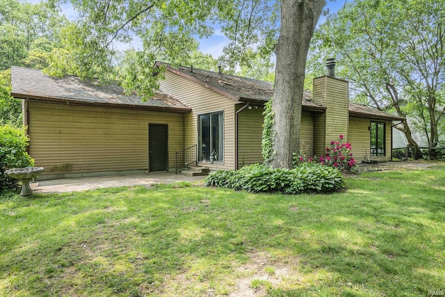 17411 Woodhurst Rd, Granger, IN 46530 - back of property featuring a lawn, a patio, a chimney, and entry steps