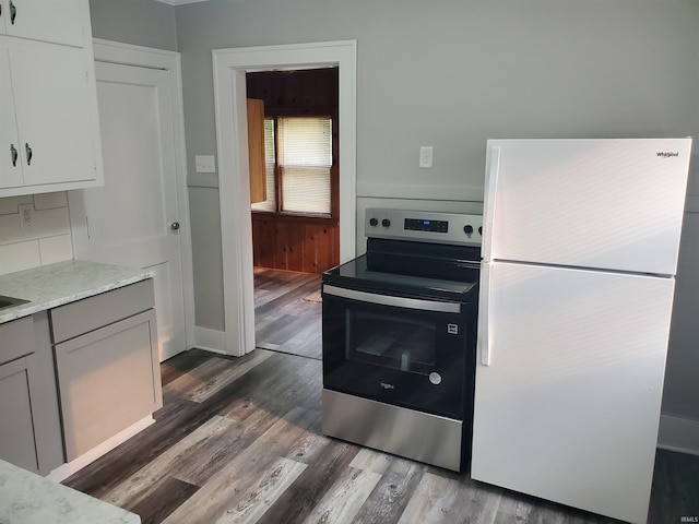 1005 E 4th St, Mishawaka, IN 46544 - kitchen with freestanding refrigerator, electric stove, dark wood finished floors, white cabinets, and decorative backsplash