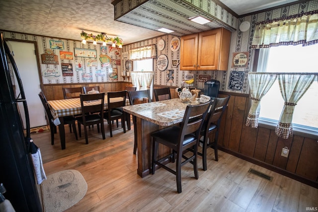12350 Cedar Rd, Bourbon, IN 46504 - dining room featuring wallpapered walls, light wood-style flooring, and a wainscoted wall