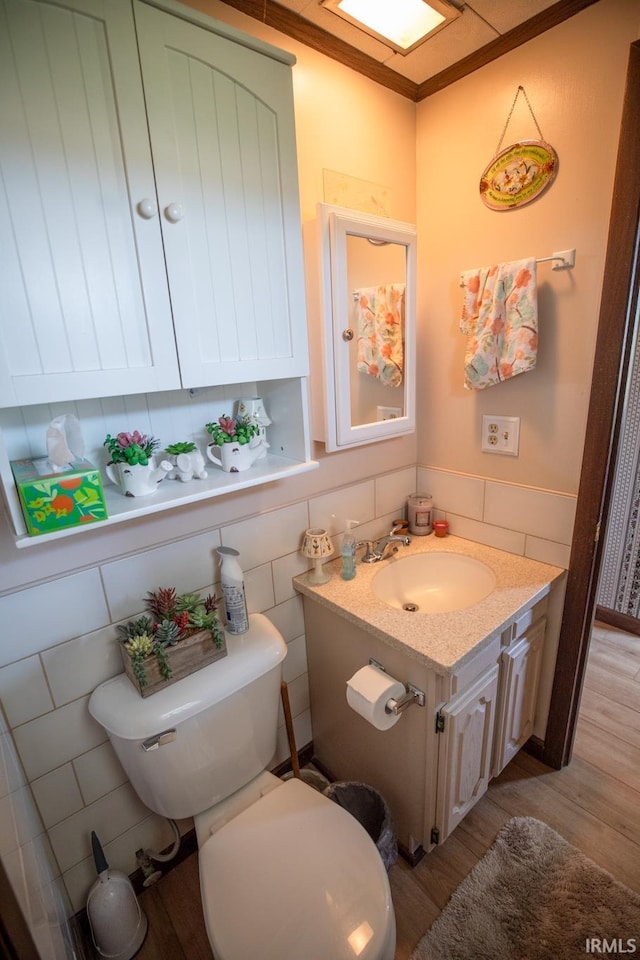 12350 Cedar Rd, Bourbon, IN 46504 - bathroom featuring wood finished floors, toilet, vanity, tile walls, and ornamental molding