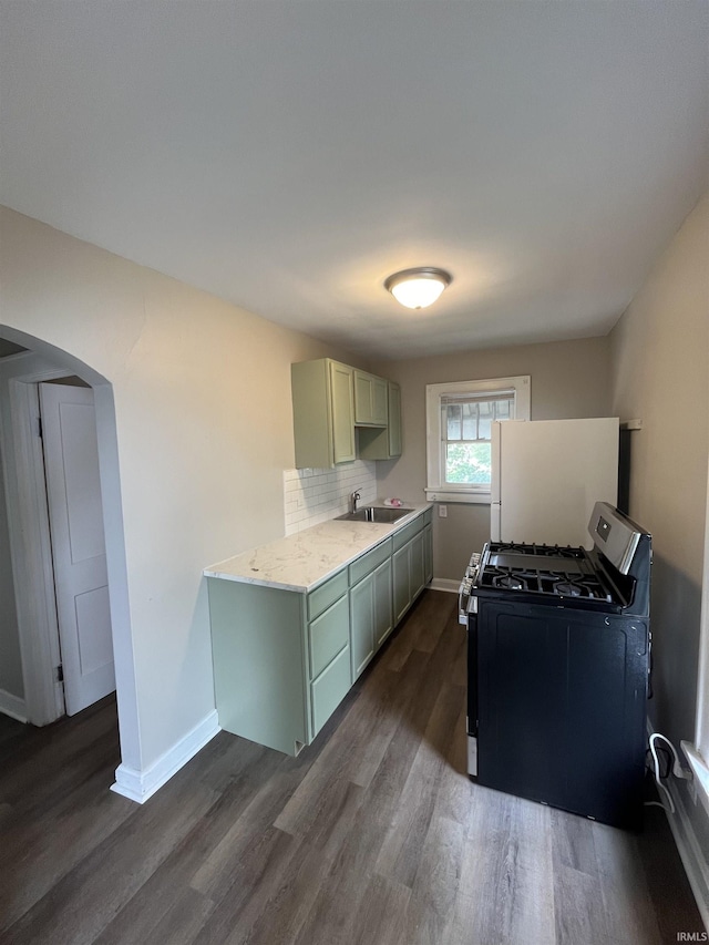 211 S Liberty St, Muncie, IN 47305 - kitchen with stainless steel range with gas stovetop, a sink, freestanding refrigerator, dark wood finished floors, and arched walkways
