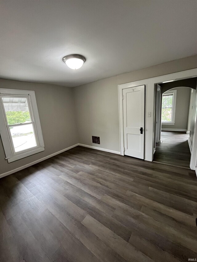 211 S Liberty St, Muncie, IN 47305 - spare room with arched walkways, dark wood-style floors, and baseboards