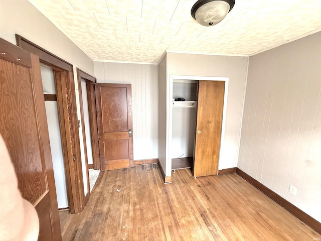 1228 Woodward Ave, New Castle, IN 47362 - unfurnished bedroom with light wood-type flooring, a closet, wood walls, baseboards, and crown molding