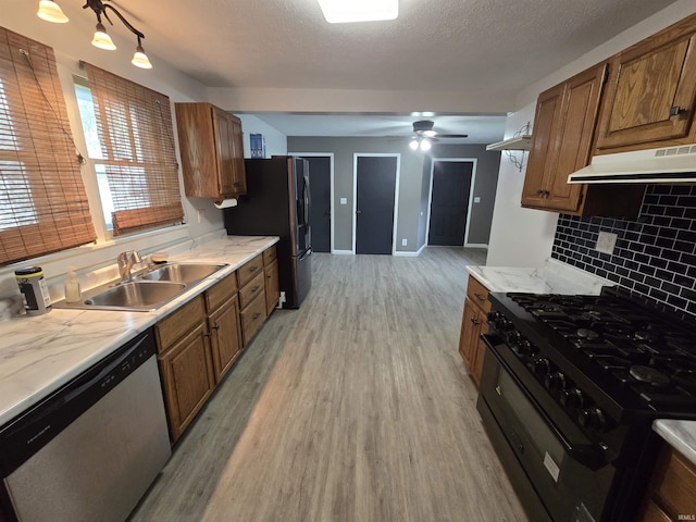 135 S 27th St, Lafayette, IN 47904 - kitchen with appliances with stainless steel finishes, under cabinet range hood, light wood-style flooring, a sink, and brown cabinets