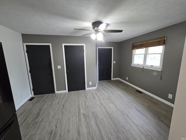 135 S 27th St, Lafayette, IN 47904 - unfurnished bedroom featuring wood finished floors, a textured ceiling, baseboards, ceiling fan, and freestanding refrigerator