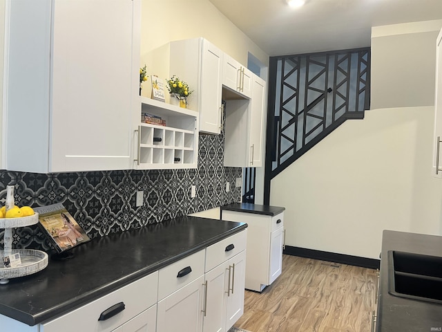 1302 Linden Ave, South Bend, IN 46628 - kitchen with dark countertops, light wood-style floors, backsplash, and white cabinetry