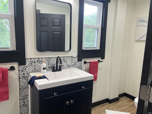 1302 Linden Ave, South Bend, IN 46628 - bathroom with vanity, wood finished floors, decorative backsplash, and toilet