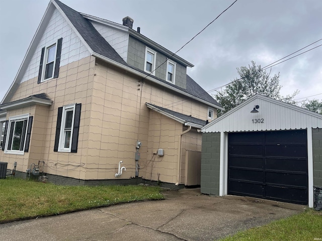 1302 Linden Ave, South Bend, IN 46628 - view of property exterior featuring an outdoor structure, central AC unit, asphalt driveway, a detached garage, and roof with shingles