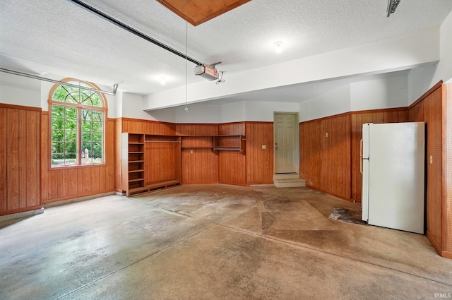 6011 W Wallen Rd, Fort Wayne, IN 46818 - garage with freestanding refrigerator, wood walls, wainscoting, and a garage door opener