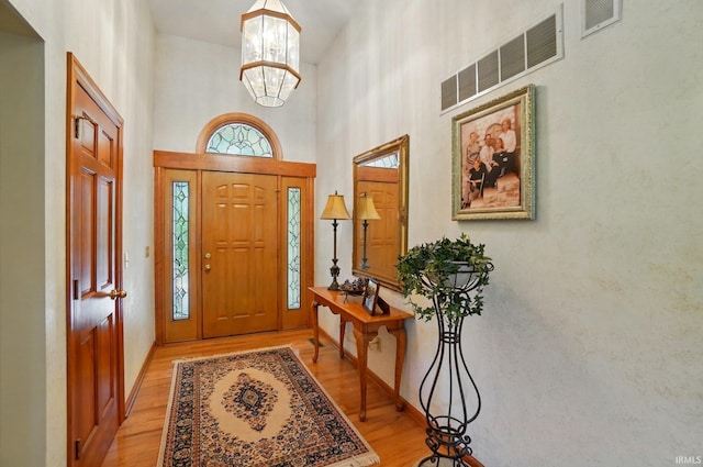 6011 W Wallen Rd, Fort Wayne, IN 46818 - foyer featuring light wood-style floors, a high ceiling, a chandelier, and baseboards