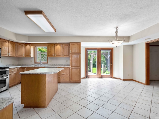 509 Water Meade Pl, Fort Wayne, IN 46825 - kitchen featuring stainless steel stove, brown cabinets, light countertops, a center island, and a textured ceiling
