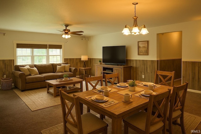 7458 E Lincolnway Rd, Columbia City, IN 46725 - carpeted dining area with a wainscoted wall, wooden walls, a ceiling fan, and a chandelier