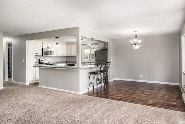 1708 Canterbury Dr, Elkhart, IN 46514 - kitchen with stainless steel appliances, dark carpet, a chandelier, baseboards, and white cabinets