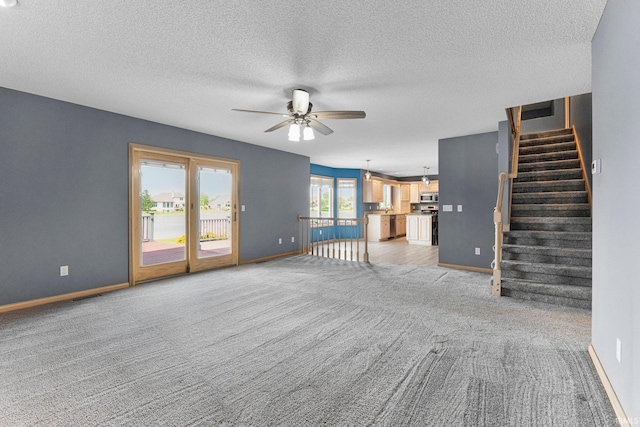 9529 Skipjack Cv, Fort Wayne, IN 46835 - unfurnished living room featuring a ceiling fan, light carpet, baseboards, stairs, and a textured ceiling