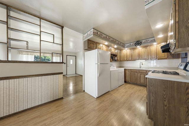 1209 E Water St, Mount Vernon, IN 47620 - kitchen featuring white appliances, light wood-type flooring, a sink, light countertops, and tasteful backsplash