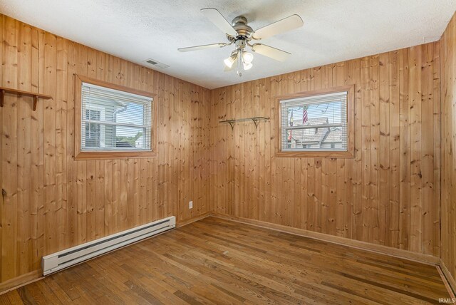 8056 E N Rd, Syracuse, IN 46567 - empty room with a baseboard radiator, healthy amount of natural light, wood finished floors, wooden walls, and baseboards