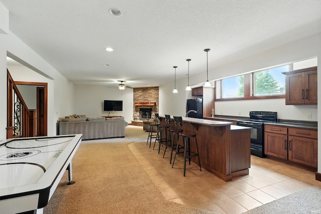16265 Gemma Pass, Huntertown, IN 46748 - kitchen featuring black appliances, a kitchen breakfast bar, a fireplace, ceiling fan, and pendant lighting