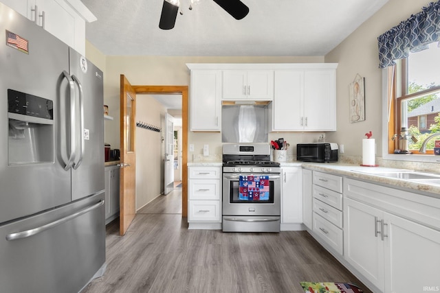 913 Cedar St, Elkhart, IN 46514 - kitchen with stainless steel appliances, a ceiling fan, white cabinets, and light wood finished floors