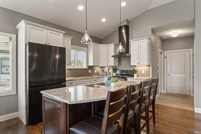 7503 Toscana Ct, Granger, IN 46530 - kitchen with freestanding refrigerator, wall chimney range hood, vaulted ceiling, stainless steel gas range, and tasteful backsplash