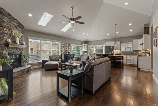 7503 Toscana Ct, Granger, IN 46530 - living room with high vaulted ceiling, ceiling fan, dark wood-style flooring, a stone fireplace, and a skylight