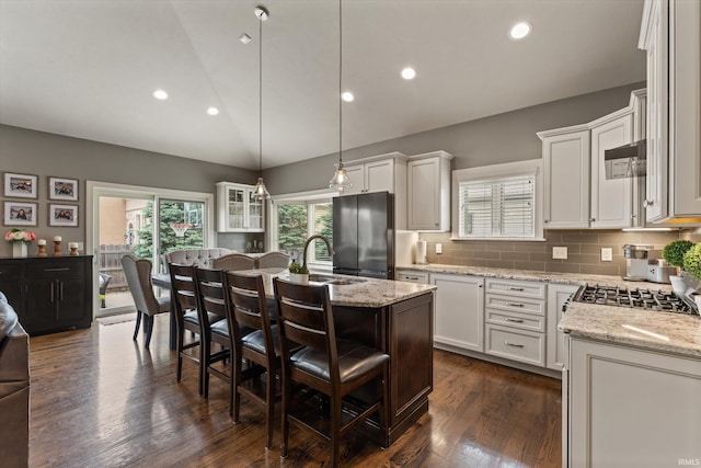 7503 Toscana Ct, Granger, IN 46530 - kitchen featuring freestanding refrigerator, a sink, an island with sink, dark wood-style flooring, and lofted ceiling
