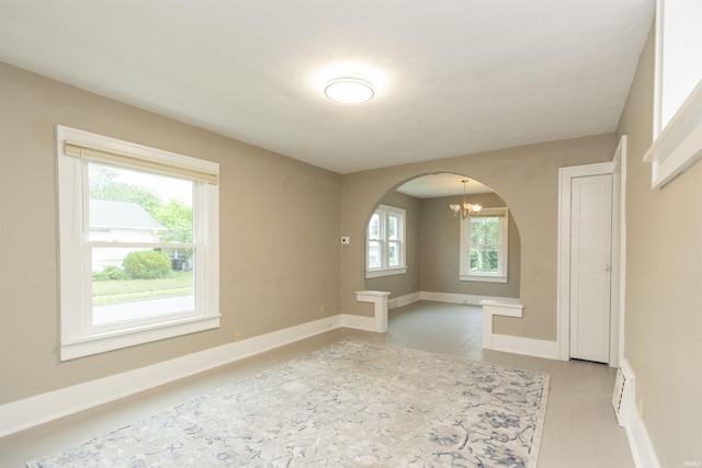 1002 S 33rd St, South Bend, IN 46615 - spare room with arched walkways, a chandelier, baseboards, and light wood-style floors