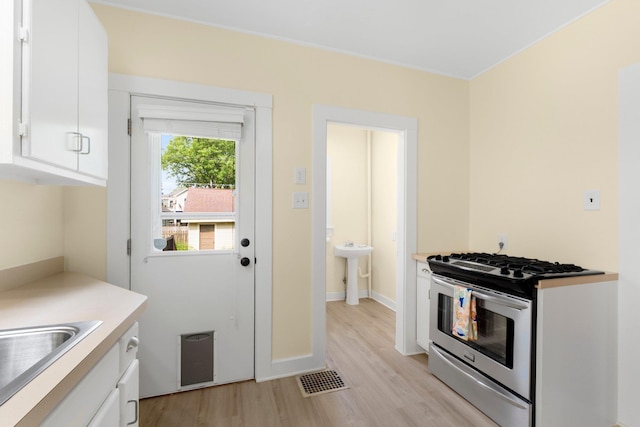 3712 Arlington Ave, Fort Wayne, IN 46807 - kitchen with stainless steel gas range, light wood finished floors, white cabinets, and light countertops