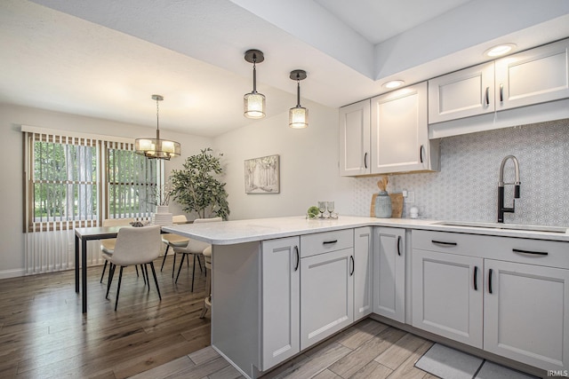 15711 Durham Way, Granger, IN 46530 - kitchen featuring a sink, a peninsula, light countertops, light wood-type flooring, and decorative backsplash