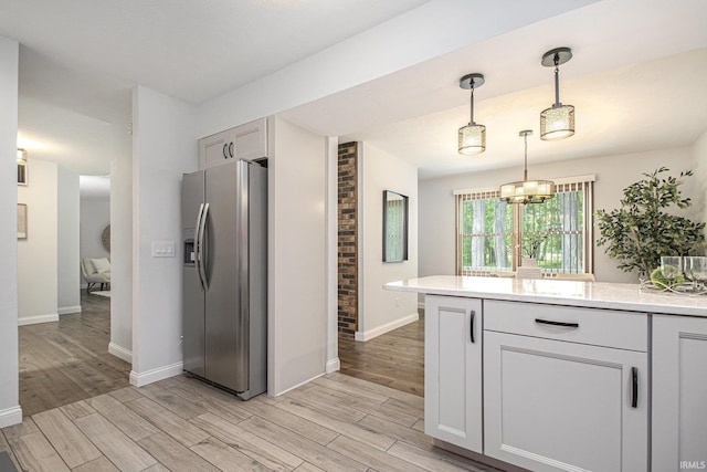 15711 Durham Way, Granger, IN 46530 - kitchen with stainless steel refrigerator with ice dispenser, light wood-style flooring, baseboards, decorative light fixtures, and light stone countertops