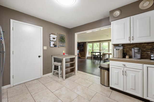 2408 W Sheffield Dr, Muncie, IN 47304 - kitchen featuring backsplash, white cabinets, light tile patterned floors, light countertops, and baseboards