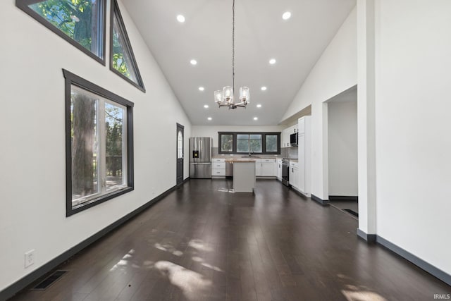 6226 Wheeling Ave, Muncie, IN 47304 - unfurnished living room with recessed lighting, a chandelier, high vaulted ceiling, healthy amount of natural light, and dark wood-style flooring