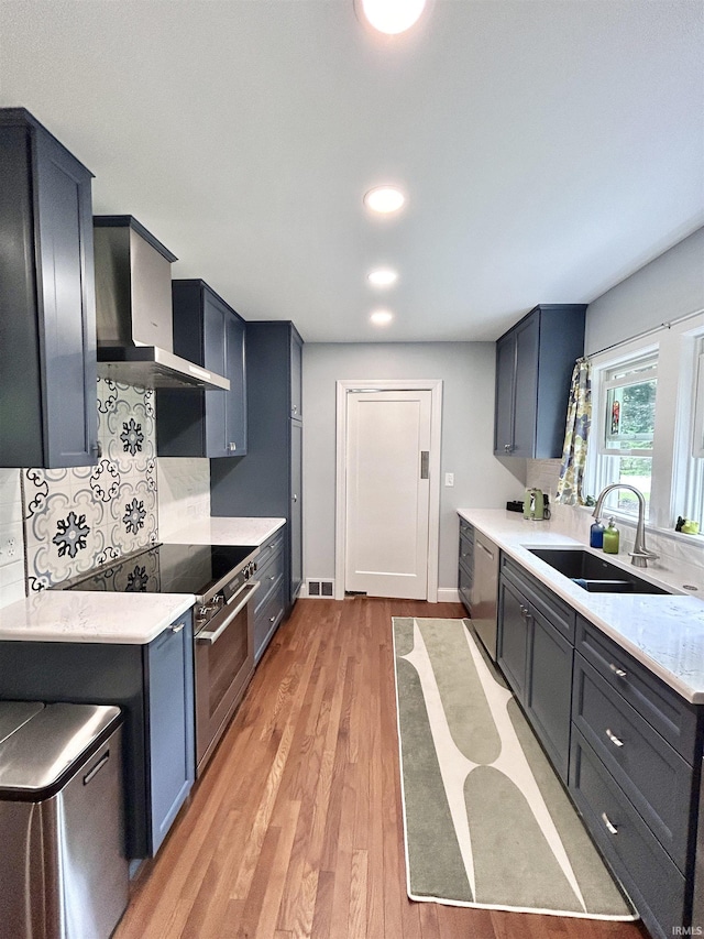 1500 N Grant St, West Lafayette, IN 47906 - kitchen with a sink, stainless steel appliances, wall chimney range hood, light wood-style flooring, and light countertops