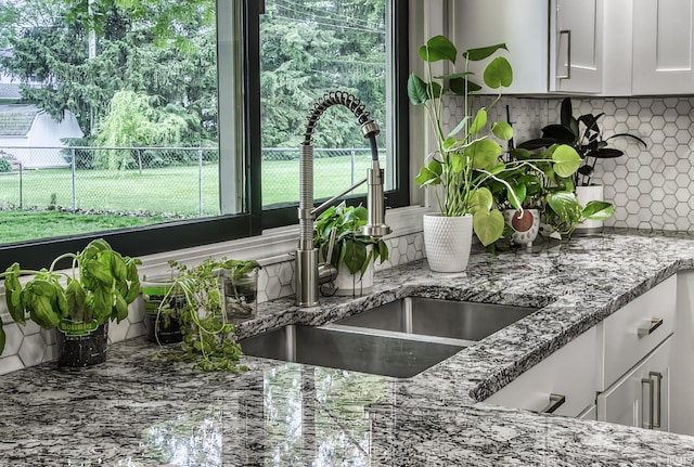 1212 Summit Ave, Bluffton, IN 46714 - kitchen view of a sink, decorative backsplash, light stone counters, and white cabinetry