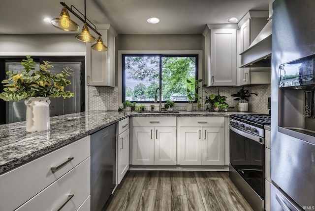 1212 Summit Ave, Bluffton, IN 46714 - kitchen with stainless steel appliances, wall chimney range hood, a sink, dark wood-style floors, and dark stone counters