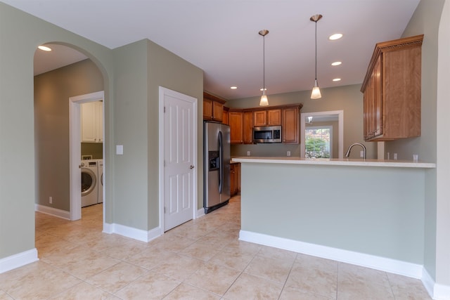 9081 Halston Cir, Newburgh, IN 47630 - kitchen with stainless steel appliances, washer / clothes dryer, a peninsula, light countertops, and brown cabinetry