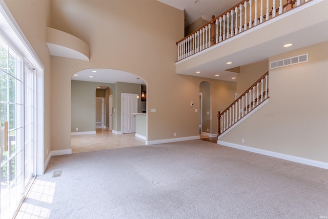 9081 Halston Cir, Newburgh, IN 47630 - unfurnished living room with arched walkways, light colored carpet, a high ceiling, baseboards, and stairway