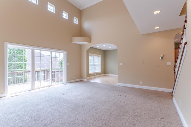 9081 Halston Cir, Newburgh, IN 47630 - empty room featuring light carpet, arched walkways, a towering ceiling, baseboards, and stairs