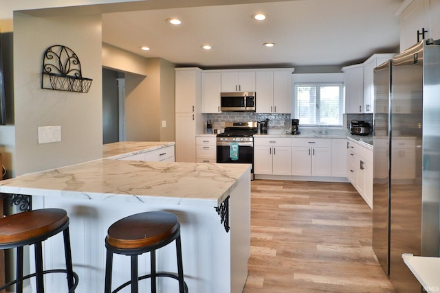 5547 N W Shafer Dr, Monticello, IN 47960 - kitchen with appliances with stainless steel finishes, light wood-style flooring, tasteful backsplash, a breakfast bar area, and recessed lighting