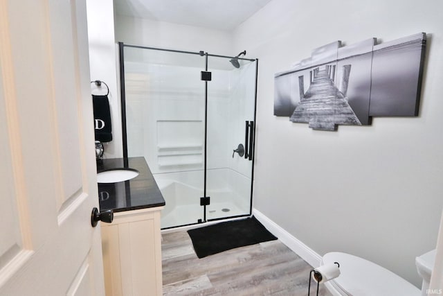 5547 N W Shafer Dr, Monticello, IN 47960 - bathroom featuring wood finished floors, a stall shower, toilet, vanity, and baseboards