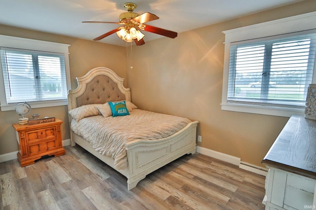 5547 N W Shafer Dr, Monticello, IN 47960 - bedroom with baseboard heating, wood finished floors, baseboards, and ceiling fan